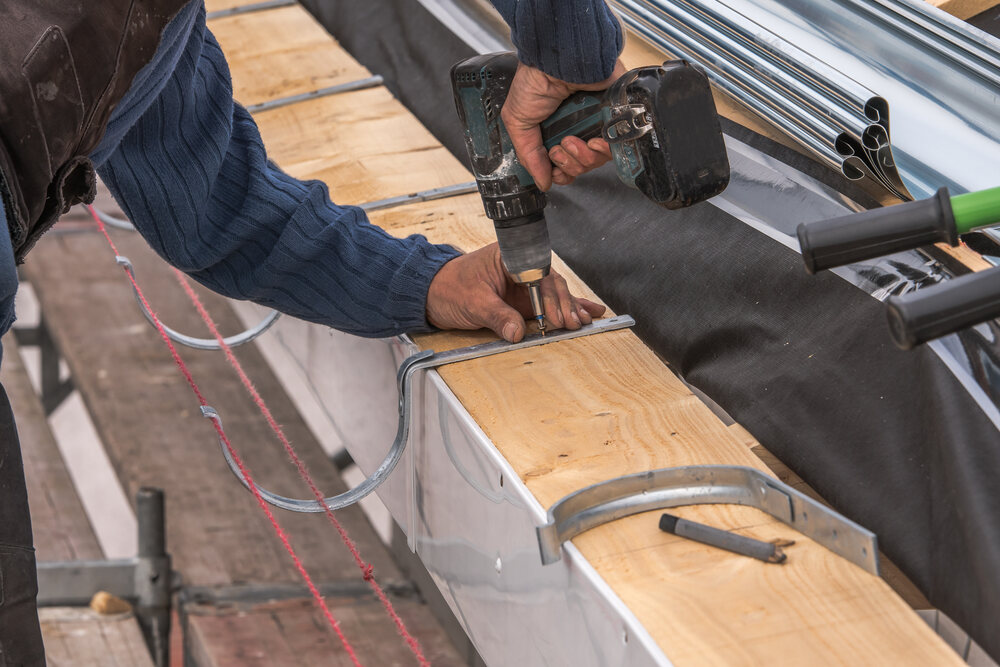 professional using drill to install gutter