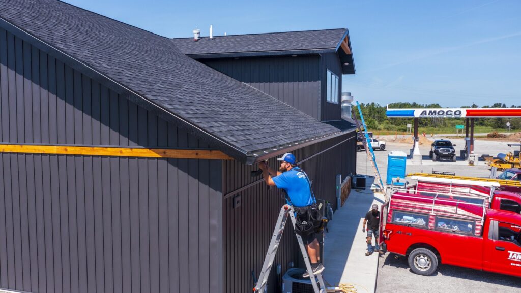 professional standing on ladder working on gutter installation of commercial building